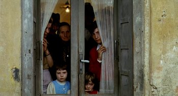 Movie still from “Teorema” (1968), directed by Pier Paolo Pasolini – A group of adults and children looking out of a window; Medium shot, High angle