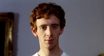 Movie still from “Teorema” (1968), directed by Pier Paolo Pasolini – A man with curly red hair is posing for a picture; Close Up shot, Low angle