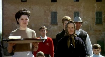 Movie still from “Teorema” (1968), directed by Pier Paolo Pasolini – A group of people standing in front of a brick building; Medium shot, Low angle