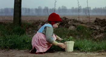 Movie still from “Teorema” (1968), directed by Pier Paolo Pasolini – A little girl in a red hat picking flowers from the ground; Medium shot, High angle