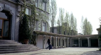 Movie still from “Teorema” (1968), directed by Pier Paolo Pasolini – A man walking down the sidewalk in front of a building; Extreme Wide shot, Low angle