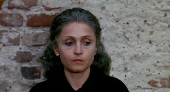 Movie still from “Teorema” (1968), directed by Pier Paolo Pasolini – A person wearing a black shirt near a brick wall; Close Up shot, High angle