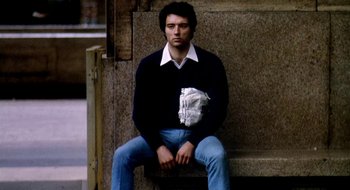 Movie still from “Teorema” (1968), directed by Pier Paolo Pasolini – A man sitting on the ground wearing a jacket; Medium shot, Low angle