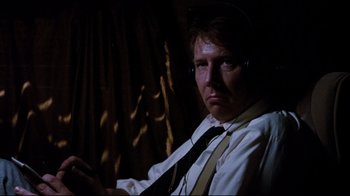Movie still from “Tequila Sunrise” (1988), directed by Robert Towne – A man wearing headphones and a white dress shirt; Close Up shot, Low angle