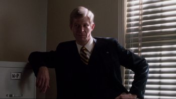 Movie still from “Tequila Sunrise” (1988), directed by Robert Towne – An older man wearing a suit and tie in front of a window; Medium shot, Low angle