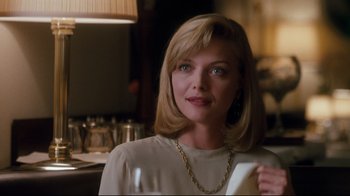 Movie still from “Tequila Sunrise” (1988), directed by Robert Towne – A woman sitting at a table in a room; Close Up shot, Over the shoulder angle