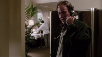 Movie still from “Tequila Sunrise” (1988), directed by Robert Towne – A man talking on a phone while standing in a room; Medium shot, Low angle