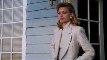 Movie still from “Tequila Sunrise” (1988), directed by Robert Towne – A woman in a white suit standing in front of a house; Medium shot, Low angle