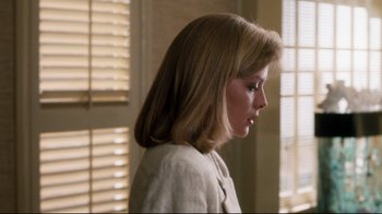 Movie still from “Tequila Sunrise” (1988), directed by Robert Towne – A young woman with long blonde hair is looking down; Close Up shot, Over the shoulder angle