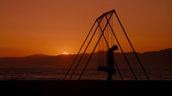 A person standing on the beach at sunset
