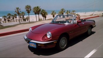 Movie still from “Tequila Sunrise” (1988), directed by Robert Towne – A woman is driving a red car down the street; Wide shot, High angle