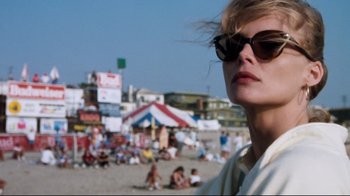 Movie still from “Tequila Sunrise” (1988), directed by Robert Towne – A woman wearing sunglasses standing on a sandy beach; Close Up shot, Low angle