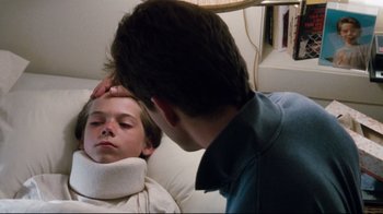 Movie still from “Tequila Sunrise” (1988), directed by Robert Towne – A young boy with a neck brace is being comforted by a young man; Close Up shot, Low angle