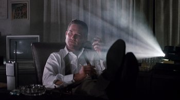 Movie still from “Tequila Sunrise” (1988), directed by Robert Towne – A man sitting in front of a window holding a cell phone; Medium shot, Low angle