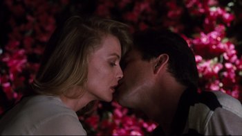 Movie still from “Tequila Sunrise” (1988), directed by Robert Towne – A man and a woman kissing in front of flowers; Close Up shot, Low angle