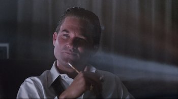 Movie still from “Tequila Sunrise” (1988), directed by Robert Towne – A man smoking a cigarette while wearing a white shirt and black tie; Close Up shot, Low angle