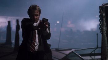 Movie still from “Tequila Sunrise” (1988), directed by Robert Towne – A man in a suit and tie holding a gun; Medium shot, Low angle
