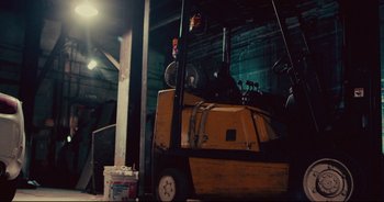 Movie still from “Terrifier” (2016), directed by Damien Leone – A forklift parked inside of a warehouse next to a building; Wide shot, Low angle