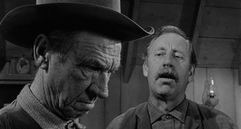 Movie still from “Terror in a Texas Town” (1958), directed by Joseph H. Lewis – A man in a cowboy hat and another man in a suit and tie; Close Up shot, Low angle