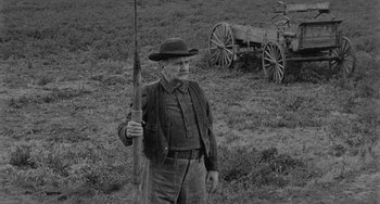 Movie still from “Terror in a Texas Town” (1958), directed by Joseph H. Lewis – An old man holding a rifle in a field; Medium shot, Low angle