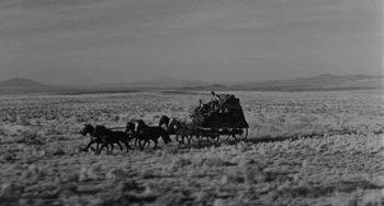 Movie still from “Terror in a Texas Town” (1958), directed by Joseph H. Lewis – A group of horses pulling a wagon full of people in a field; Extreme Wide shot, Low angle
