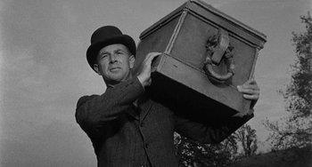Movie still from “Terror in a Texas Town” (1958), directed by Joseph H. Lewis – A man in a top hat carrying a trunk; Medium shot, Low angle