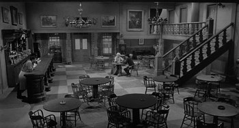 Movie still from “Terror in a Texas Town” (1958), directed by Joseph H. Lewis – A black and white photo of two people sitting at a table in a restaurant; Extreme Wide shot, High angle