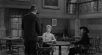 Movie still from “Terror in a Texas Town” (1958), directed by Joseph H. Lewis – A man and a woman sitting at a table in front of a fireplace; Wide shot, Over the shoulder angle