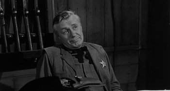 Movie still from “Terror in a Texas Town” (1958), directed by Joseph H. Lewis – An older man wearing a sheriff's star badge; Close Up shot, Over the shoulder angle