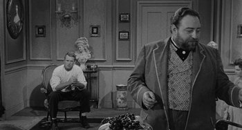 Movie still from “Terror in a Texas Town” (1958), directed by Joseph H. Lewis – Two men sitting in a living room next to each other; Medium shot, Over the shoulder angle