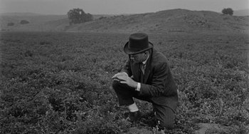 Movie still from “Terror in a Texas Town” (1958), directed by Joseph H. Lewis – A black and white photo of a man squatting in a field; Medium shot, High angle