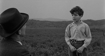 Movie still from “Terror in a Texas Town” (1958), directed by Joseph H. Lewis – An old photo of a boy and an older man in a field; Medium shot, Over the shoulder angle