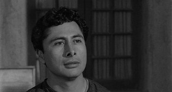 Movie still from “Terror in a Texas Town” (1958), directed by Joseph H. Lewis – Black and white photograph of a young man in front of a book shelf; Close Up shot, Low angle