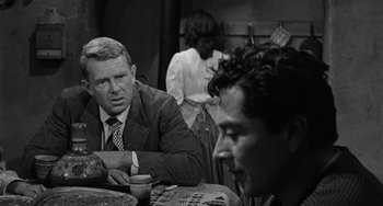 Movie still from “Terror in a Texas Town” (1958), directed by Joseph H. Lewis – A man sitting at a table with two other people; Close Up shot, Over the shoulder angle