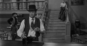 Movie still from “Terror in a Texas Town” (1958), directed by Joseph H. Lewis – A black and white photo of a man and a woman in front of a staircase; Medium shot, Over the shoulder angle