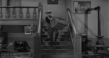 Movie still from “Terror in a Texas Town” (1958), directed by Joseph H. Lewis – A man carrying a suitcase down a flight of stairs; Wide shot, High angle