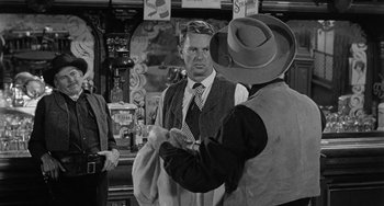 Movie still from “Terror in a Texas Town” (1958), directed by Joseph H. Lewis – A man in a suit and a cowboy hat is looking at another man in a suit; Medium shot, Over the shoulder angle