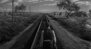 Movie still from “Terror in a Texas Town” (1958), directed by Joseph H. Lewis – A man standing on a train track in the middle of nowhere; Wide shot, High angle