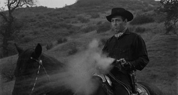 Movie still from “Terror in a Texas Town” (1958), directed by Joseph H. Lewis – A man wearing a cowboy hat while riding a horse; Medium shot, Low angle