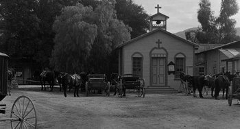 Movie still from “Terror in a Texas Town” (1958), directed by Joseph H. Lewis – A black and white photo of horses and carriages in front of a church; Extreme Wide shot, High angle