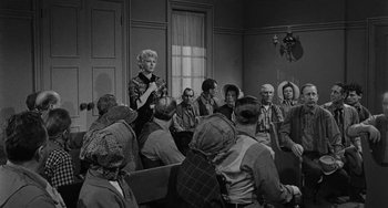 Movie still from “Terror in a Texas Town” (1958), directed by Joseph H. Lewis – An old photo of people sitting in a room; Wide shot, Over the shoulder angle