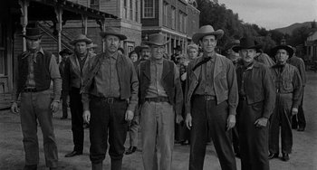 Movie still from “Terror in a Texas Town” (1958), directed by Joseph H. Lewis – A black and white photo of a group of men standing in front of buildings; Medium shot, Low angle