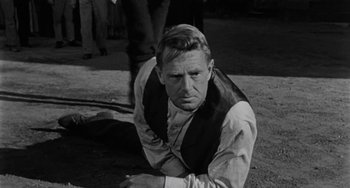 Movie still from “Terror in a Texas Town” (1958), directed by Joseph H. Lewis – A black and white photo of a man crouching down; Medium shot, High angle