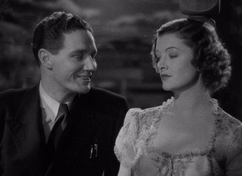 Movie still from “Test Pilot” (1938), directed by Victor Fleming – A man standing next to a woman wearing a dress; Close Up shot, High angle