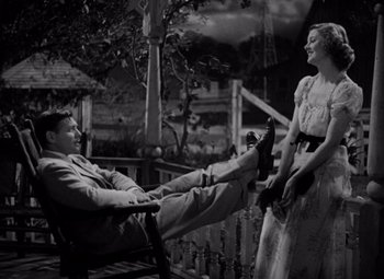 Movie still from “Test Pilot” (1938), directed by Victor Fleming – A man and a woman sitting on a bench in front of a tree; Wide shot, High angle