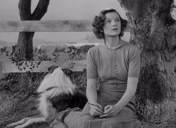 Movie still from “Test Pilot” (1938), directed by Victor Fleming – A woman sitting on the ground next to a dog; Medium shot, High angle