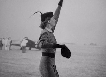Movie still from “Test Pilot” (1938), directed by Victor Fleming – An old photo of a woman holding a frisbee; Medium shot, Low angle