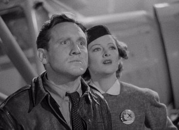 Movie still from “Test Pilot” (1938), directed by Victor Fleming – An old photo of a man and a woman standing next to each other; Medium shot, Low angle