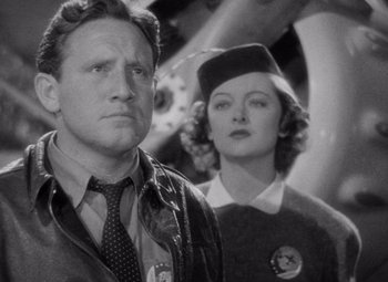 Movie still from “Test Pilot” (1938), directed by Victor Fleming – A man and a woman standing next to each other in a black and white photo; Medium shot, Low angle