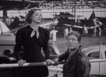 Movie still from “Test Pilot” (1938), directed by Victor Fleming – A man and a woman holding hands in an airplane hangar; Medium shot, Low angle